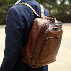 Brown leather backpack worn by a person with a blurred natural background